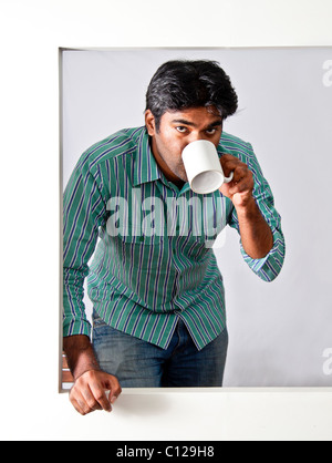 young man having a beverage at an open window Stock Photo
