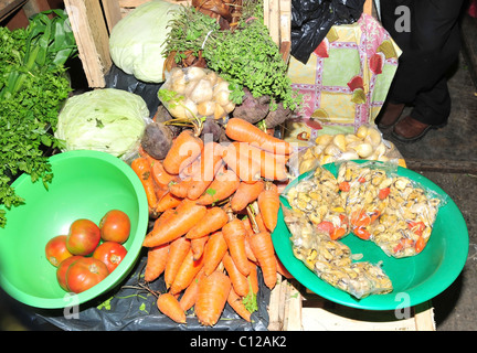 Fresh food, green vegetables red tomatoes and mussels on shelf of an indoor market stall, Feria Municipal, Ancud, Chiloe, Chile Stock Photo