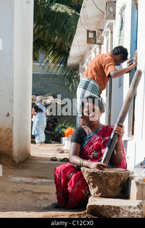 Indian woman using stone / wood mortar and pestle, pounding ingredients to make chutney. Andhra Pradesh, India Stock Photo