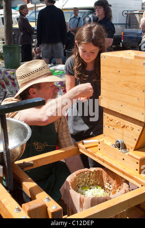 At Sebastopol farmer's market, volunteer hands cup of freshly pressed apple juice to a young girl. Stock Photo