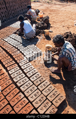 Indian men making house bricks by hand using a mould and wet clay / mud. Drying them in the sun before firing them hard. Andhra Pradesh, India Stock Photo