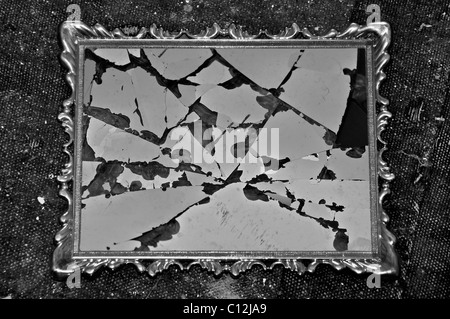 Antique picture frame with broken glass on dirty rag background. Black and white. Stock Photo