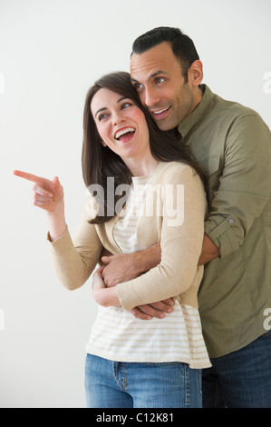 Happy couple embracing and looking away, studio shot Stock Photo