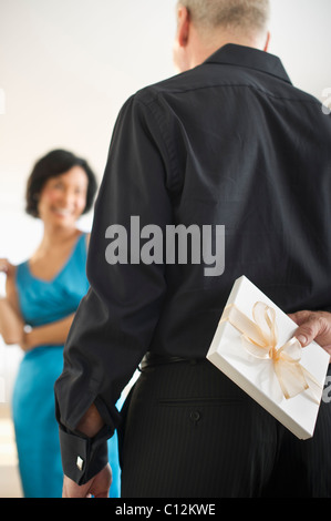 USA, New Jersey, New Jersey City, Man hiding gift box behind his back Stock Photo