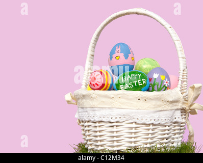 Basketful of colorful Easter eggs against purple background, with copy space Stock Photo