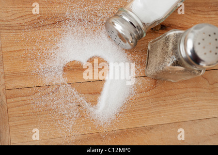 Heart shaped spilt salt on table Stock Photo