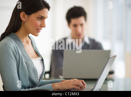 USA, New Jersey, Jersey City, business man and woman using laptops in office Stock Photo