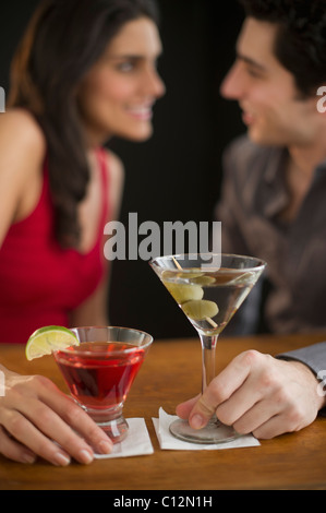 Young couple having drinks and flirting, studio shot Stock Photo