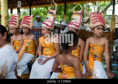 Young girlswearing the traditional costume of a temple dancer watching a performance at a temple festival in Padang Bai, Bali, Indonesia Stock Photo