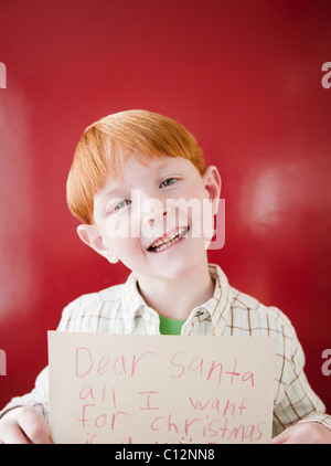 Studio portrait of boy (8-9) holding letter to Santa Stock Photo