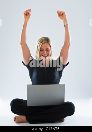 Young woman using laptop, celebrating Stock Photo