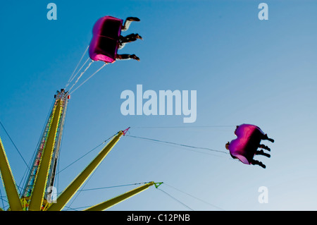 Low angle view of people on a fairground ride, with a blue sky Stock Photo