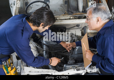 Auto mechanic with an apprentice repairing a car in a garage Stock Photo