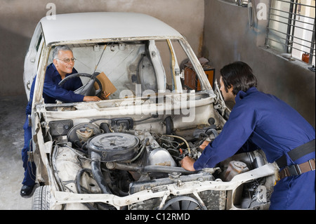 Auto mechanic with an apprentice repairing a car in a garage Stock Photo
