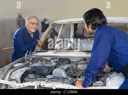 Auto mechanic with an apprentice repairing a car in a garage Stock Photo