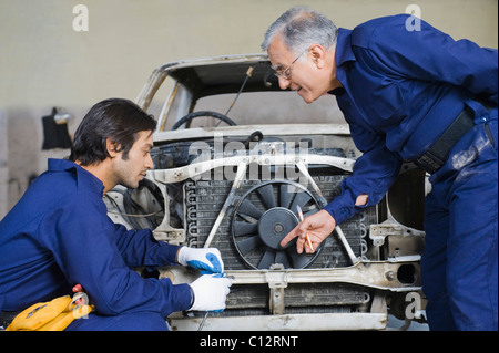 Auto mechanic with an apprentice repairing a car in a garage Stock Photo