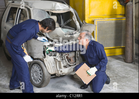 Auto mechanic with an apprentice repairing a car in a garage Stock Photo