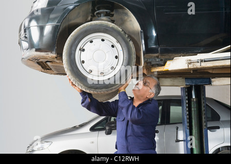 Auto mechanic working on a car wheel in a garage Stock Photo