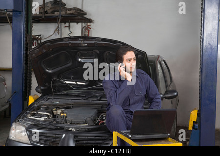 Auto mechanic talking on a mobile phone in a garage Stock Photo