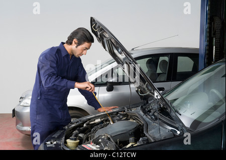 Auto mechanic checking oil level of a car in a garage Stock Photo