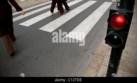 People crossing the road at red light on pedestrian crossing Stock Photo