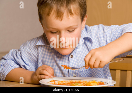 portrait of young boy eating pasta Stock Photo