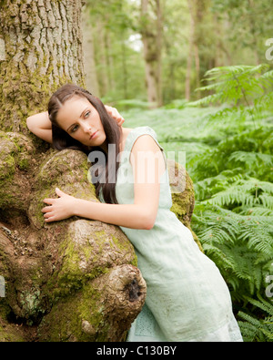 portrait of young woman leaning against tree Stock Photo