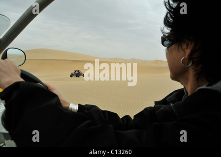 Scene of woman driving 4X4 dune buggy in desert on ATV tour Swakopmund Namibia Travel Transportation Vacations action Sport Stock Photo