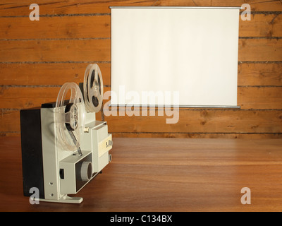 Film projector aimed at the screen hanging on the log wall Stock Photo