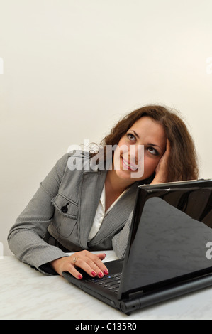Inspired businesswoman looking upwards at something leaning on the table with a laptop Stock Photo
