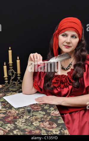 Charming senior lady in red antique dress writing a letter Stock Photo