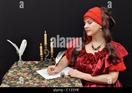 Charming senior lady in red antique dress writing a letter Stock Photo