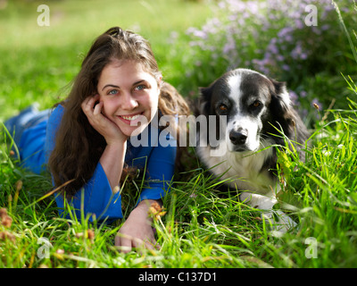 USA, Colorado, Portrait of young woman relaxing with dog on grass Stock Photo