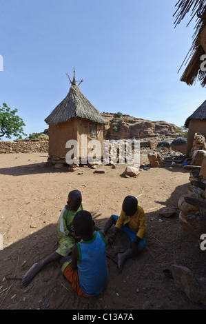 Children playing in a courtyard in front of a granary.  Begnemato. Dogon Plateau, Mali. Stock Photo