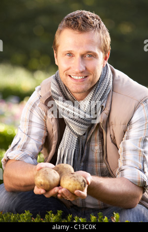Young man posing with potatoes in garden Stock Photo