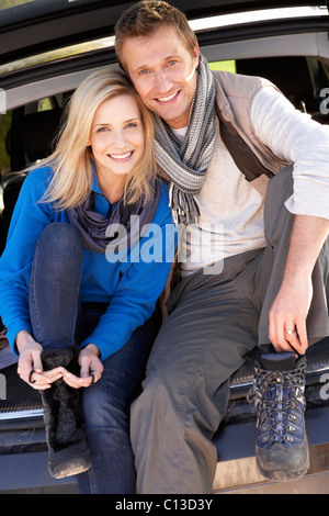 Young couple pose together at rear of car Stock Photo
