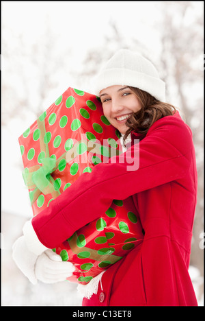 USA, Utah, Lehi, Portrait of young woman hugging Christmas gift outdoors Stock Photo