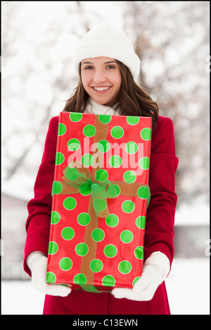 USA, Utah, Lehi, Portrait of young woman holding Christmas gift outdoors Stock Photo