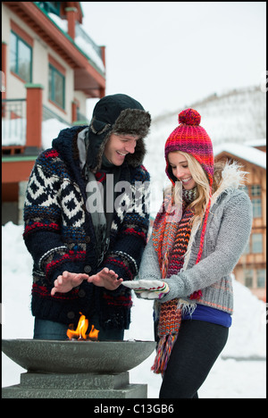USA, Utah, Salt Lake City, couple warming hands over burner in ski resort Stock Photo