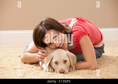 USA, Utah, Lehi, Portrait of woman embracing Labrador on carpet Stock Photo