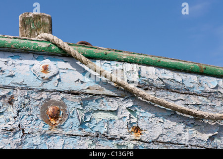 Peeling paint, old rope and rusting bolts. The gunwale of an old boat. Layers of paint peel from the sides of an old boat. Stock Photo