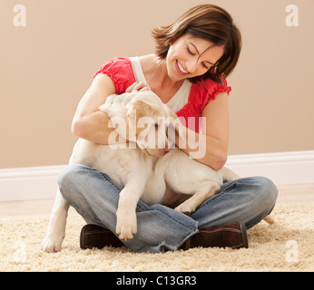 USA, Utah, Lehi, Woman embracing Labrador on carpet Stock Photo