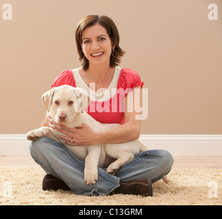 USA, Utah, Lehi, Portrait of woman embracing Labrador on carpet Stock Photo
