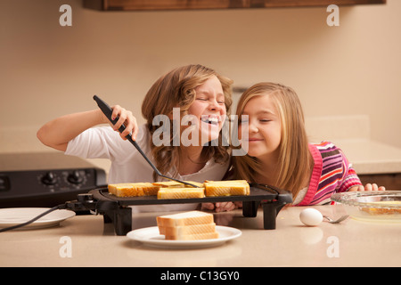 USA, Utah, Lehi, Two girls (10-11) preparing toast in kitchen Stock Photo