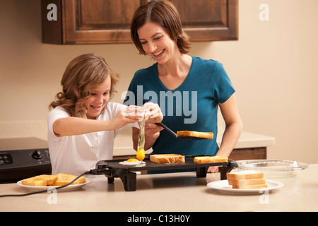 USA, Utah, Lehi, Mother preparing breakfast with daughter (10-11) in kitchen Stock Photo