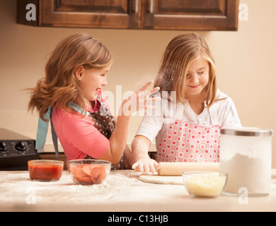 USA, Utah, Lehi, Two girls (10-11) preparing pizza in kitchen Stock Photo