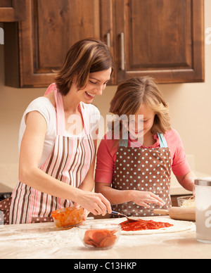 USA, Utah, Lehi, Mother and daughter (10-11) preparing pizza in kitchen Stock Photo