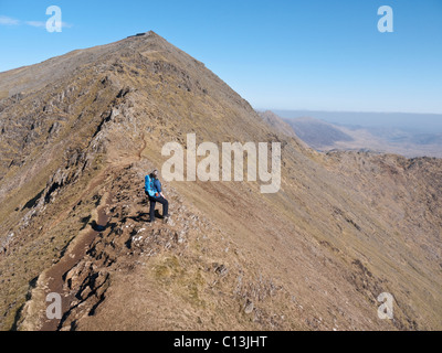 A female hill walker admires the view from Bwlch Main on Snowdon's south ridge. The café, Hafod Eryri can be seen on the summit. Stock Photo