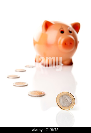 One Euro coin in font of a Piggy bank isolated over a white background Stock Photo