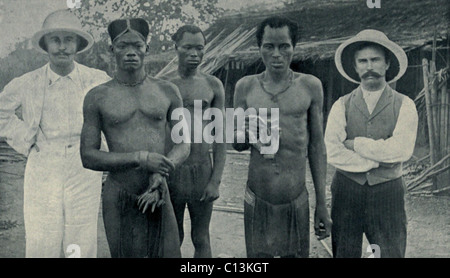 Atrocities of the Rubber Slavery in the Belgian Congo. Natives hold the severed hands of two countrymen murdered by rubber sentries in May 1904. The white men are Edgar Stannard and John Harris, Baptist missionaries, who documented many such atrocities for humanitarian activist Edward Morel. Stock Photo